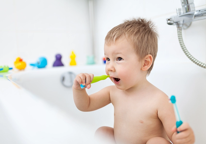 Un niño en la bañera cepillándose los dientes.