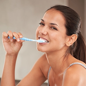 Una mujer cepillándose los dientes.