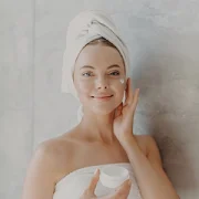 Una mujer echando crema en la cara.